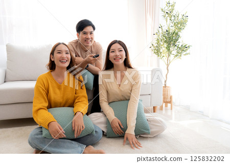 Group young asian friends watching TV together in a cozy living room at home with happy. 125832202