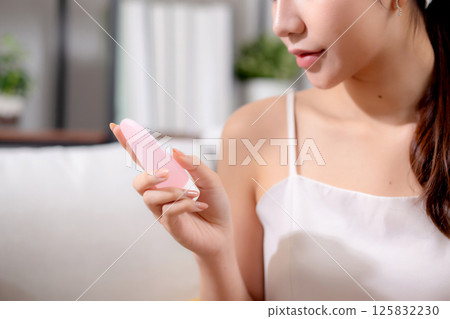 Closeup hands asian woman sitting on sofa choice cosmetic cream or lotion with shopping online. 125832230