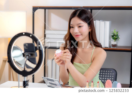 Young asian woman presenting and review cosmetic product with excitement on social media platform. 125832233
