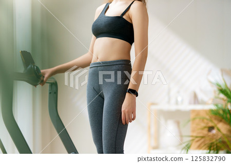 Young woman running on a treadmill indoors Young woman running on a treadmill indoors 125832790