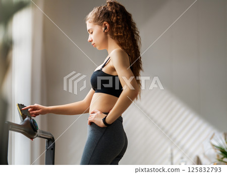 Young woman running on a treadmill indoors Young woman running on a treadmill indoors 125832793
