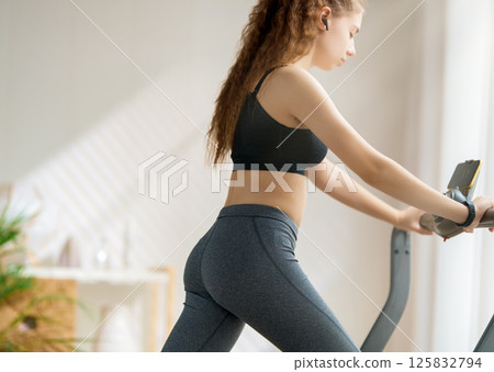Young woman running on a treadmill indoors Young woman running on a treadmill indoors 125832794
