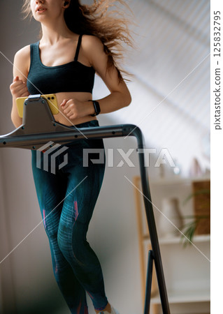 Young woman running on a treadmill indoors Young woman running on a treadmill indoors 125832795