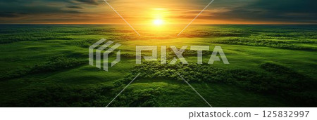 Vibrant Sunrise Over Lush Green Landscape with Expansive Fields and Rolling Hills 125832997