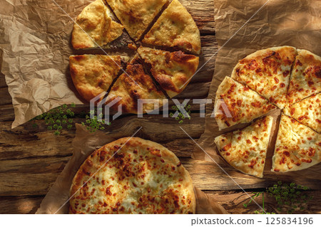A traditional khachapuri  basking in sunny light against a rustic wooden background, highlighting its golden crust and gooey cheese filling. 125834196