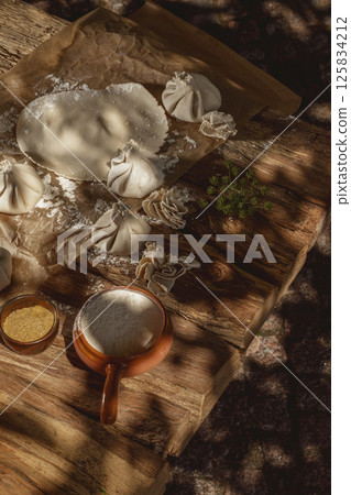 Freshly made uncooked handmade khinkali, the traditional Georgian dumplings, in bright sunlight, showcasing fresh ingredients and the art of cooking in action. 125834212