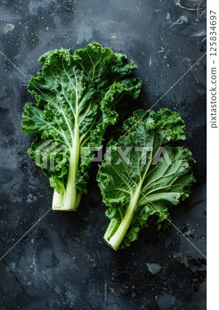 Two lush kale leaves on a dark, textured background 125834697