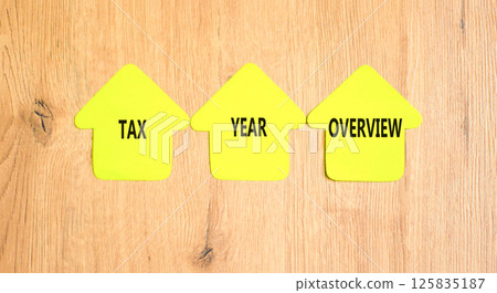 Tax year overview symbol. Concept words Tax year overview on beautiful yellow paper houses. Beautiful wooden background. Business tax year overview concept. Copy space. 125835187