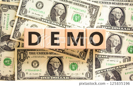 Demo symbol. Concept word Demo on beautiful wooden blocks. Dollar bills. Beautiful background from dollar bills. Business and demo concept. Copy space. 125835196