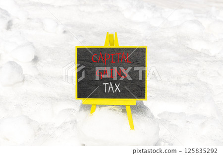 Capital gains tax symbol. Concept words Capital gains tax on beautiful blackboard. Beautiful white snow background. Business and capital gains tax concept. Copy space. 125835292