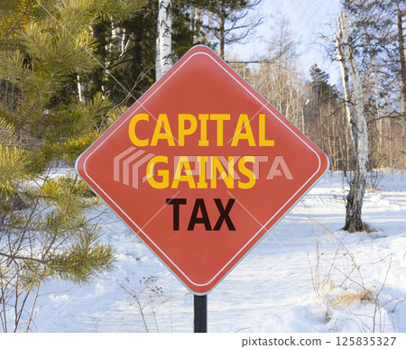 Capital gains tax symbol. Concept words Capital gains tax on beautiful red road sign. Beautiful winter forest background. Business and capital gains tax concept. Copy space. Capital gains tax symbol. Concept words Capital gains tax on beautiful red road sign. Beautiful winter forest background. Business and capital gains tax concept. Copy space. 125835327