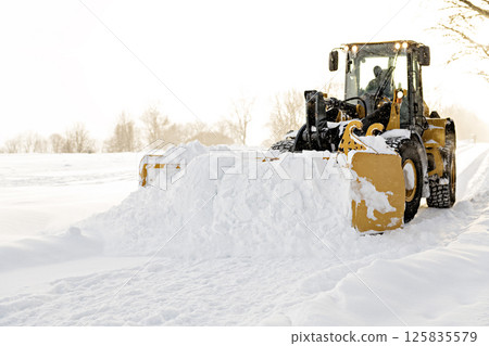 A big yellow snow plow cleaning a road 125835579