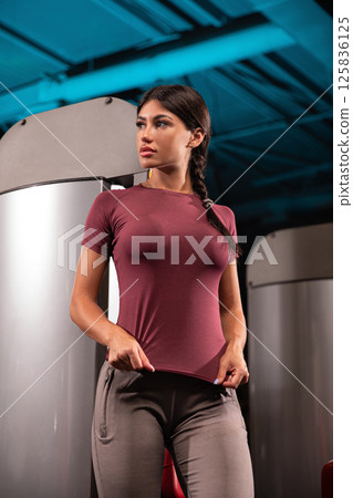 Healthy lifestyle is highlighted as fitness model poses confidently in stylish activewear within contemporary gym setting. vibrant atmosphere encourages physical activity. 125836125