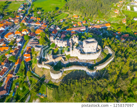 Stunning aerial view of the Rabi Castle ruins in Czechia, surrounded by lush greenery and quaint villages. Discover the historical architecture and scenic landscapes from this vantage point. 125837097