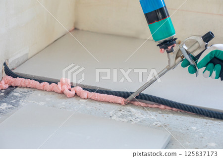 Application of foam adhesive for insulation installation 125837173