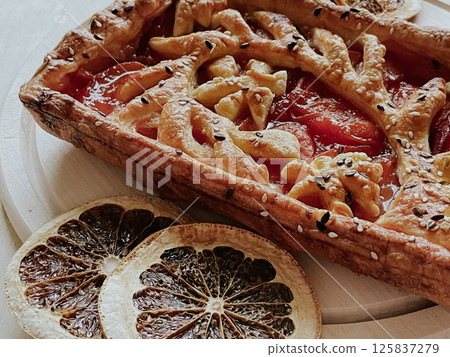 Homemade pie with jam, in the style of autumn comfort. A dried orange is laid out around the pie. Homemade pie with jam, in the style of autumn comfort. A dried orange is laid out around the pie. 125837279