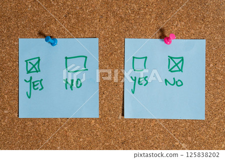 Two opposite choices pinned to cork board, making a decision Two opposite choices pinned to cork board, making a decision 125838202