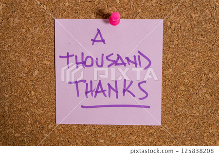 Purple sticky note on corkboard expressing a thousand thanks 125838208