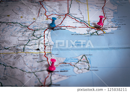Pushpins marking locations on folded road map of argentina 125838211