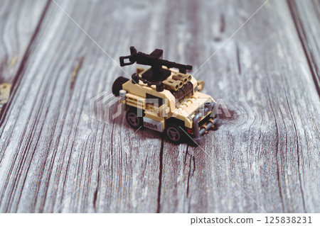 Toy military vehicle with machine gun resting on wooden surface 125838231