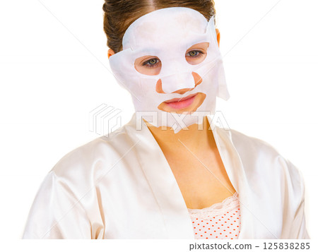 Woman applying sheet mask on face Woman applying sheet mask on face 125838285