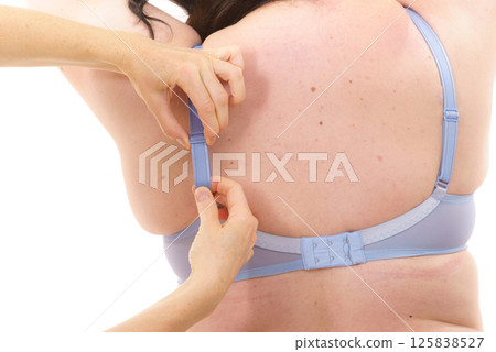 Bra fitter help plus size woman find perfect fit. Back view. Bra fitter help plus size woman find perfect fit. Back view. 125838527