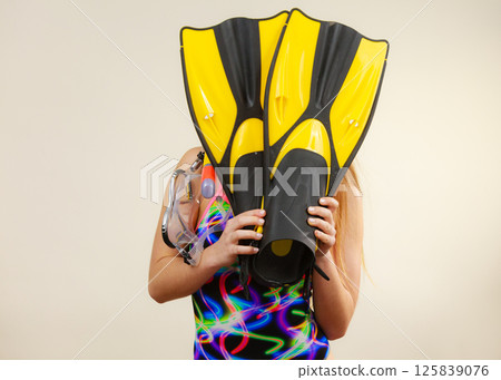 Woman covering her face with flippers having fun Woman covering her face with flippers having fun 125839076