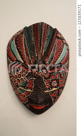 Intricate Batik Wooden Masks with Vibrant Patterns and Colors Displayed on a Neutral Background in an Indonesian Artisan Setting 125839171