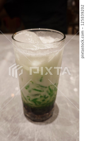 Iced Cendol Dessert in a Glass on Marble Table with Creamy and Green Layers Iced Cendol Dessert in a Glass on Marble Table with Creamy and Green Layers 125839202