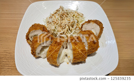 Crispy Tonkatsu Served with Shredded Cabbage on White Plate with Wooden Table Background in Restaurant Setting Crispy Tonkatsu Served with Shredded Cabbage on White Plate with Wooden Table Background in Restaurant Setting 125839235