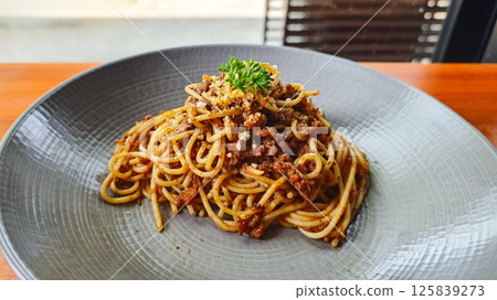 Plate of Spaghetti Bolognese on Grey Plate on Wooden Table in Restaurant Setting Plate of Spaghetti Bolognese on Grey Plate on Wooden Table in Restaurant Setting 125839273