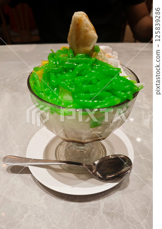 Refreshing Green Cendol Dessert in a Glass with Ice and Coconut Milk on Marble Table Refreshing Green Cendol Dessert in a Glass with Ice and Coconut Milk on Marble Table 125839286