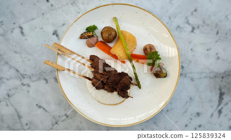 Exquisite Plated Dendeng Age Grilled Beef with Savory Sauce Vegetables and Tuber Garnish on Marble Table Exquisite Plated Dendeng Age Grilled Beef with Savory Sauce Vegetables and Tuber Garnish on Marble Table 125839324