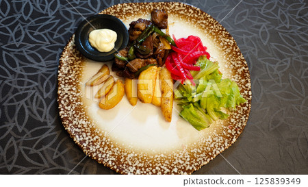 Saikoro Mongolian Beef with Wedge Potatoes and Pickled Vegetables on a Rustic Plate in an Elegant Restaurant Setting 125839349