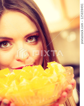 Woman holds bowl full of sliced orange fruits 125839491