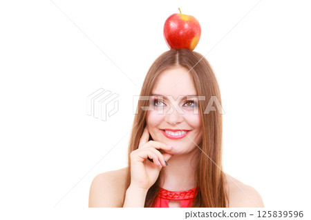 Beautiful woman holds apple fruit on head 125839596