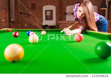 Young woman playing billiard. 125839616