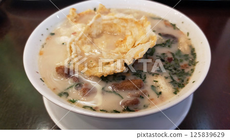 Traditional Indonesian Soto Betawi Soup with Creamy White Broth and Crispy Toppings in a Restaurant Setting 125839629
