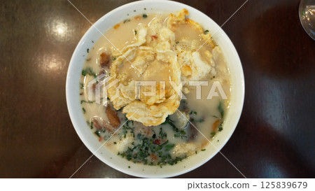 Traditional Indonesian Soto Betawi Soup with Creamy White Broth and Crispy Toppings in a Restaurant Setting 125839679
