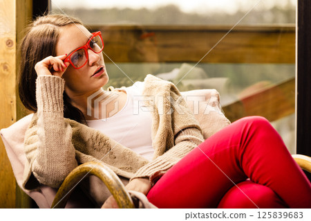 Relaxed woman wearing red glasses sitting on chair 125839683