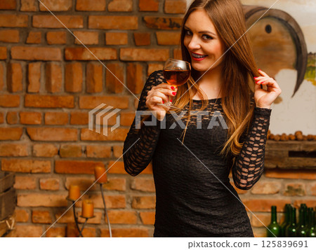 Woman tasting wine in rural cottage interior 125839691