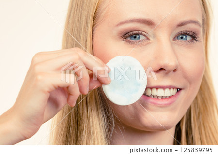 Woman cleaning her face skin with cotton pad Woman cleaning her face skin with cotton pad 125839795