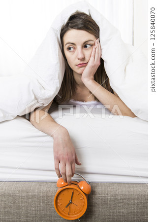 Young sleeping woman and alarm clock in bedroom at home 125840070