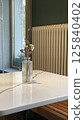 A Minimalist Table Setup Featuring Beautiful Flowers Alongside a Cozy Radiator for Ambiance 125840402