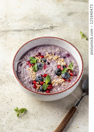 Wholegrain oatmeal porridge with blueberries, pomegranate seeds and nuts, healthy food for breakfast 125840473