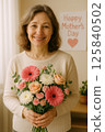 Smiling Woman Holding Flowers with Mother's Day Message in the Background 125840502