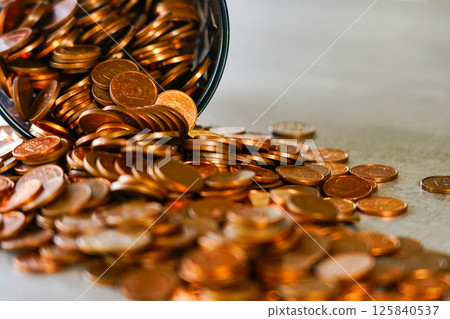 Many coins spilled from an overturned cup, concept of hoarding, success and wealth, selected focus Many coins spilled from an overturned cup, concept of hoarding, success and wealth, selected focus 125840537