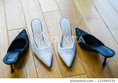 Sexy high heels mules facing each other, one small and white, the other larger and black Sexy high heels mules facing each other, one small and white, the other larger and black 125840538