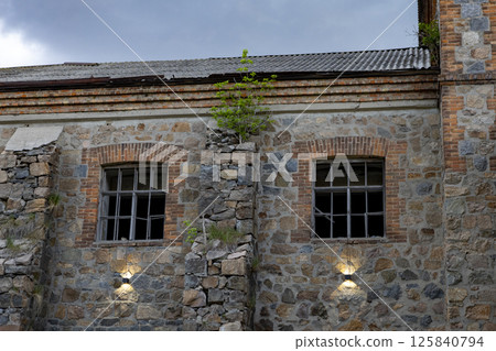 an old brick building that looks like a castle against a backdrop of storm clouds 125840794