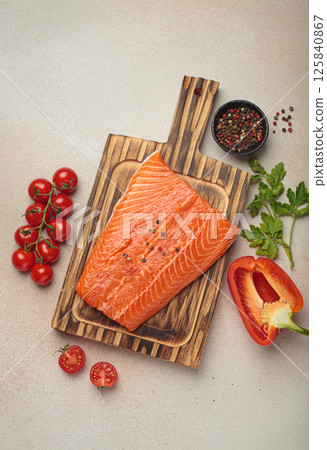 Fresh raw salmon fillet with cooking ingredients on wooden board top view on light beige background Fresh raw salmon fillet with cooking ingredients on wooden board top view on light beige background 125840867